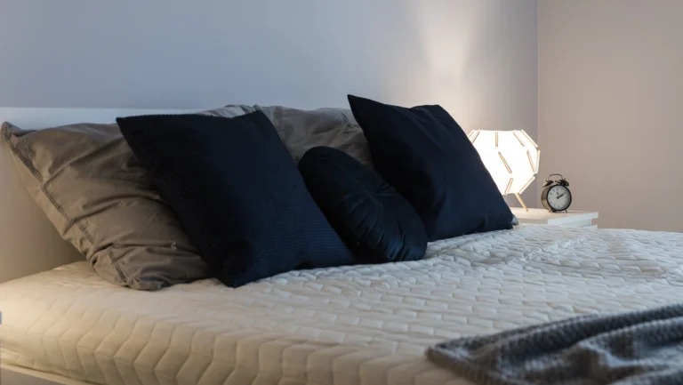 Przytulna sypialnia w nowoczesnym stylu z miękką pościelą, ciepłym oświetleniem i naturalnymi akcentami